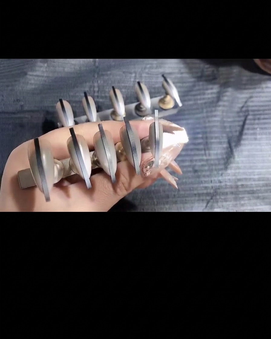 Una pinzetta che rimuove con attenzione un sottile adesivo da ununghia rifinita con airbrush.