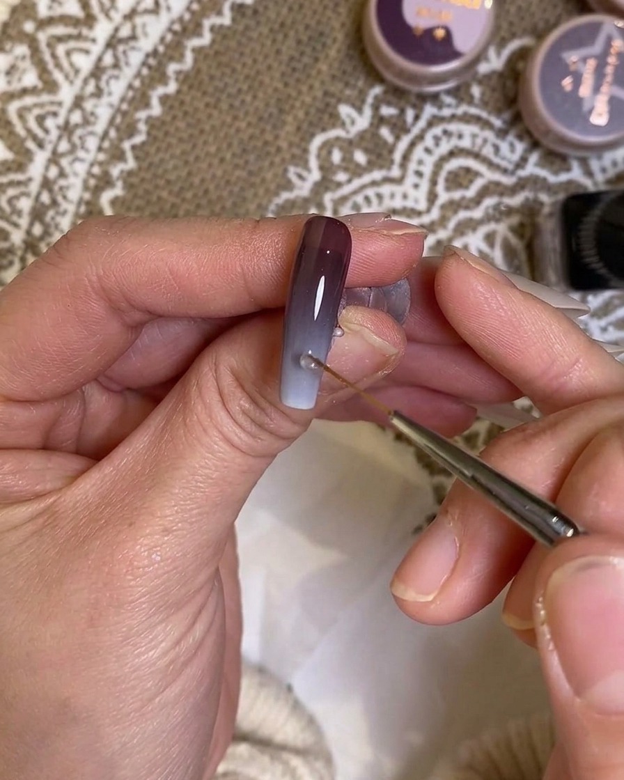 Un pennello a punta sottile che sfuma il punto di incontro tra bianco e viola.
