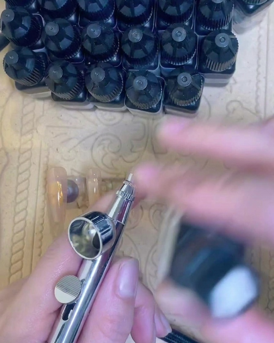 Primo piano di un pennello che applica una base gel trasparente sullunghia naturale.