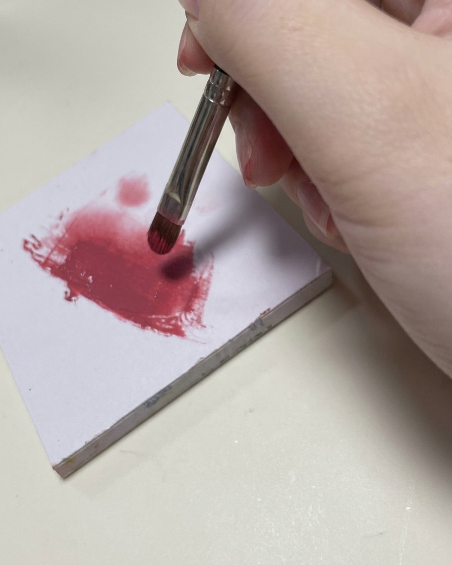 Un piccolo pennello per nail art sfuma il gel rosa sulla sezione centrale dellunghia.