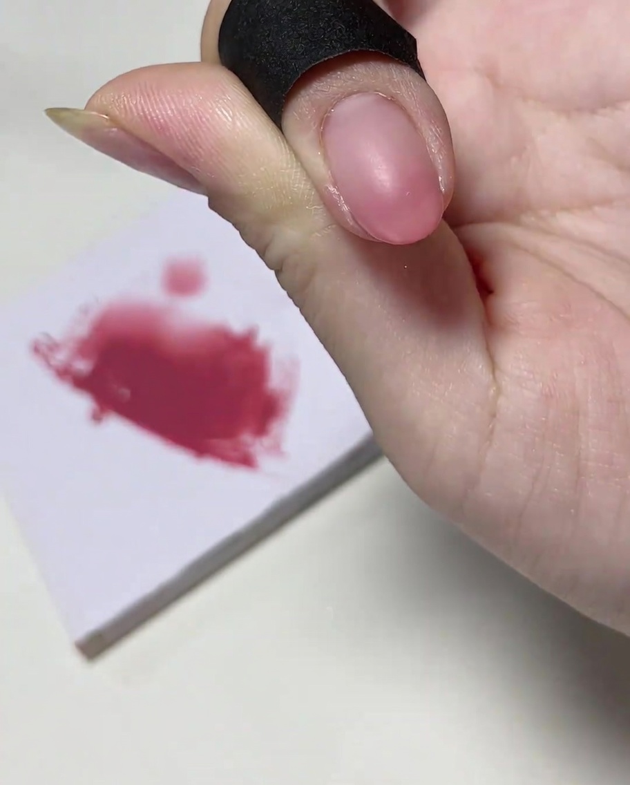 Un pennello per unghie aggiunge una quantità concentrata di gel rosa sulla punta dellunghia.