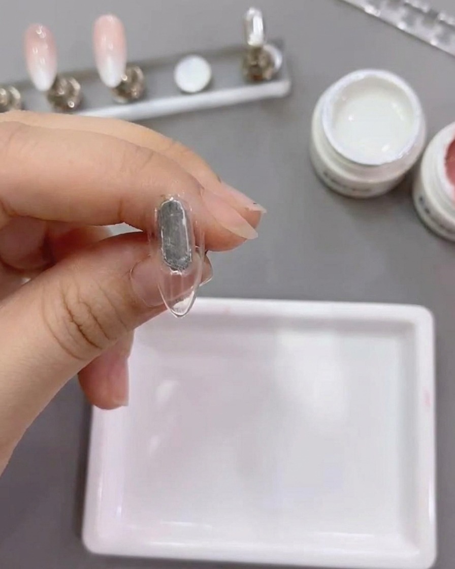 Un pennello piatto applica il gel bianco numero 79 sulla punta di ununghia naturale.
