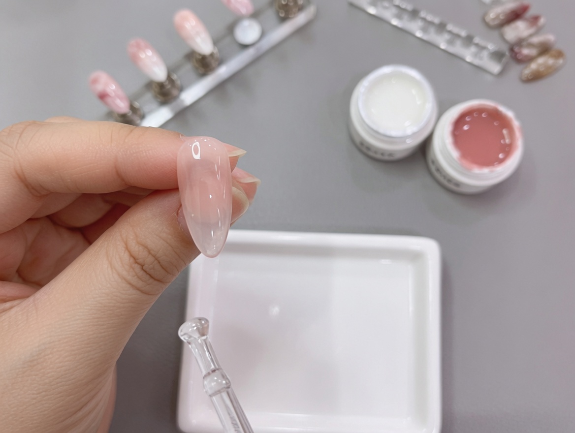 Primo piano di una mano con un design ombré nude-bianco mentre viene inserita sotto la lampada UV per la polimerizzazione finale.
