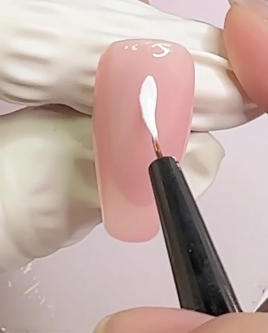 Ununghia nude con due linee bianche incrociate che formano un motivo a X al centro.