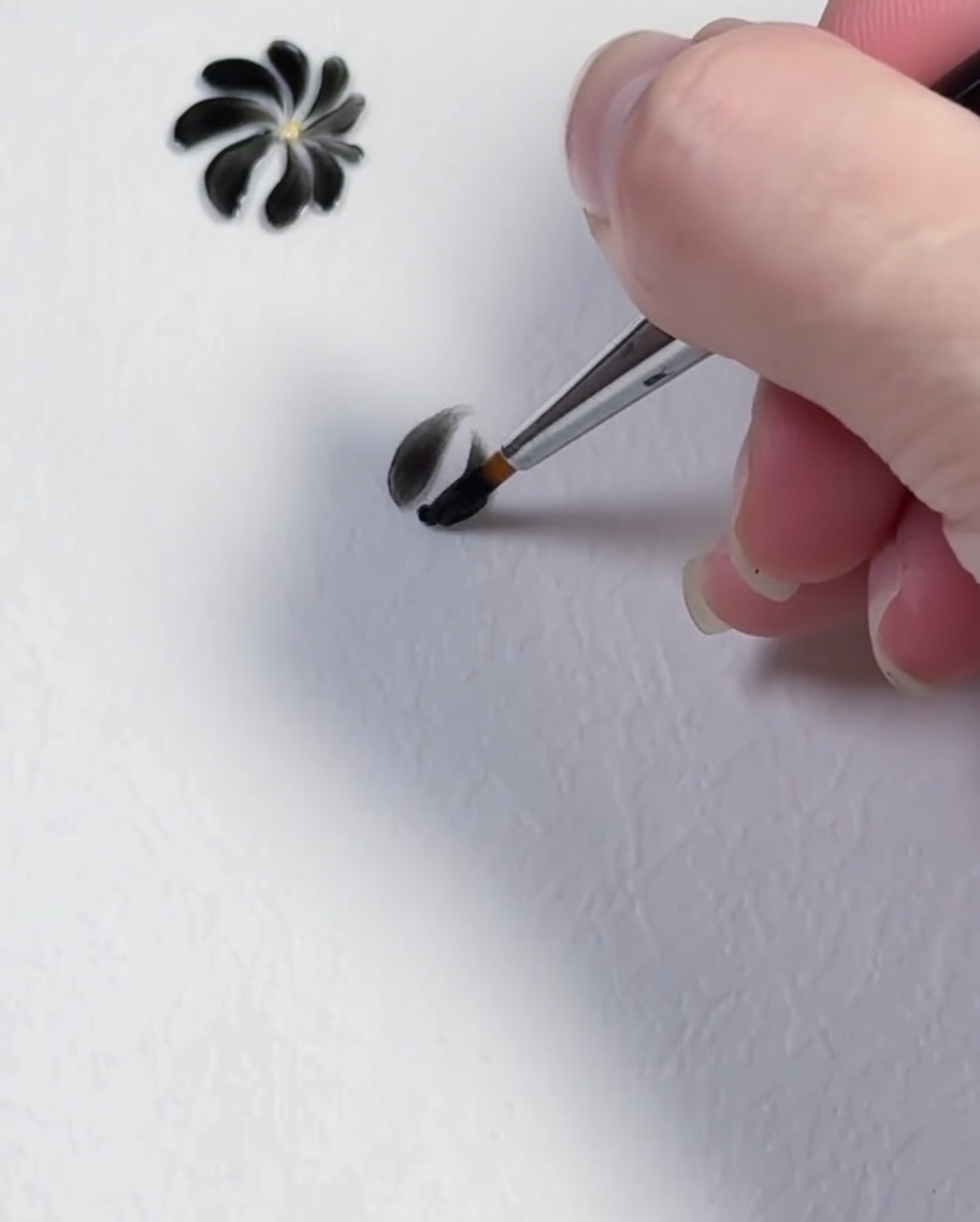 Una pennellata che forma il terzo petalo nero di un design a margherita.