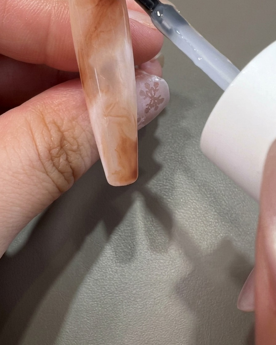 Un pennello applica il top coat trasparente sopra un design marmorizzato completato.