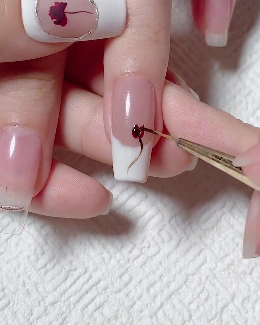 Primo piano di un pennello che aggiunge profondità alla rosa con smalto gel rosso.