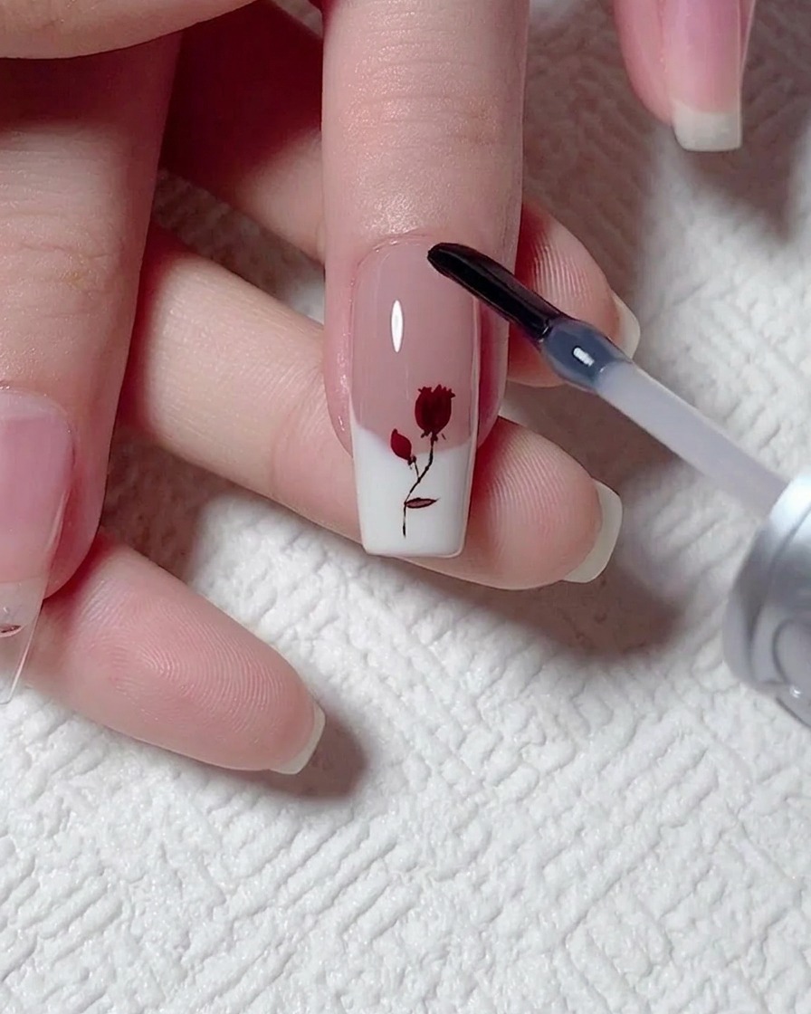 Un pennello che applica uno strato liscio di gel di rinforzo trasparente sopra una decorazione a rosa.