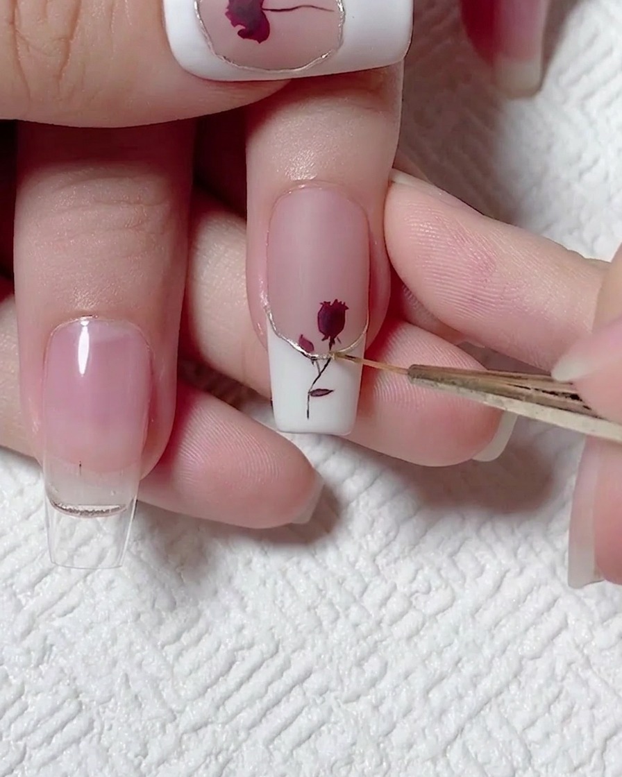 Primo piano di un pennello liner che applica top coat sopra un accento dorato su una French.