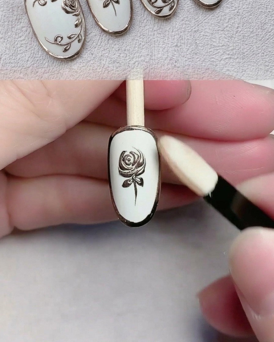 Un applicatore in spugna per ombretto che lucida la polvere cromata oro su un design per unghie dettagliato.