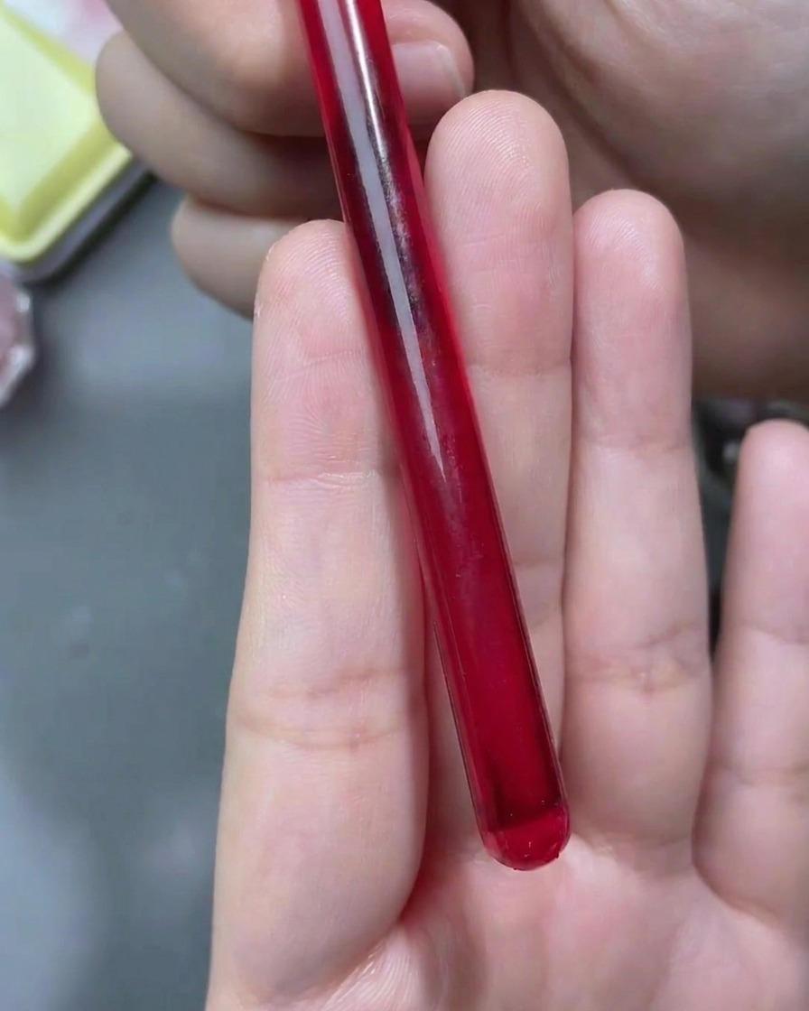 Un pennello a punta fine che disegna contorni di rose bianche su ununghia con finitura opaca.