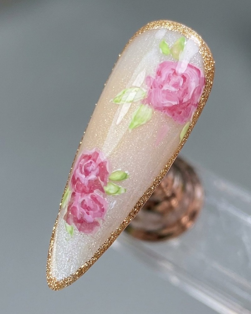 Primo piano di un design a rosa finito che viene tracciato con un delicato bordo in gel color platino scintillante.