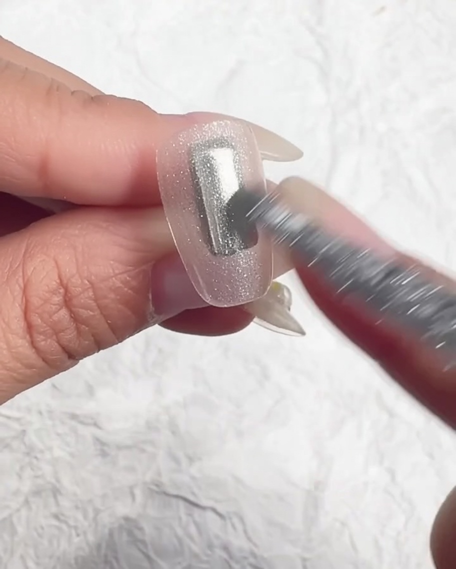 Un pennello livella il gel effetto ghiaccio sullunghia.
