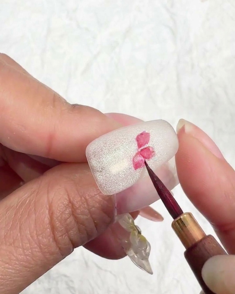 Dettaglio di un design a fiore di ciliegio su ununghia, con pigmento rosa più chiaro aggiunto alle punte dei petali.