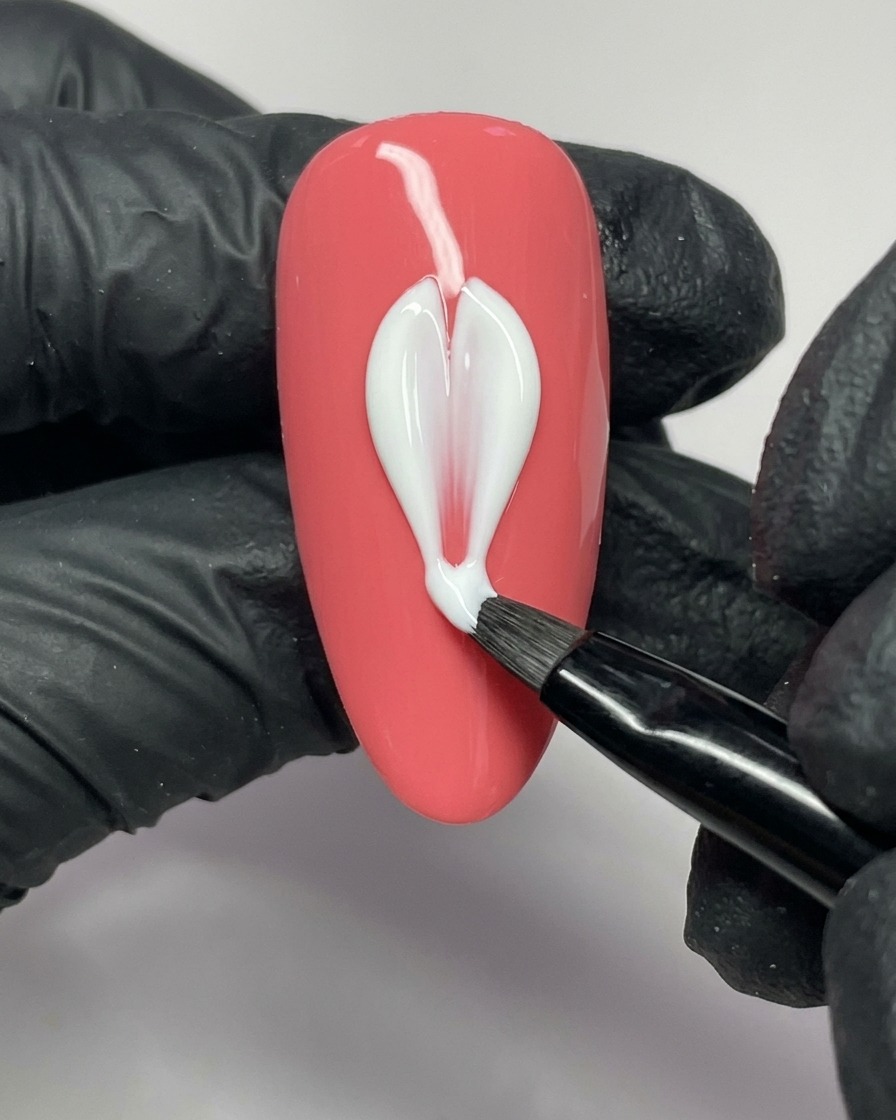 Un pennello per nail art applica del gel bianco per formare il lato sinistro di un petalo su ununghia rosa.