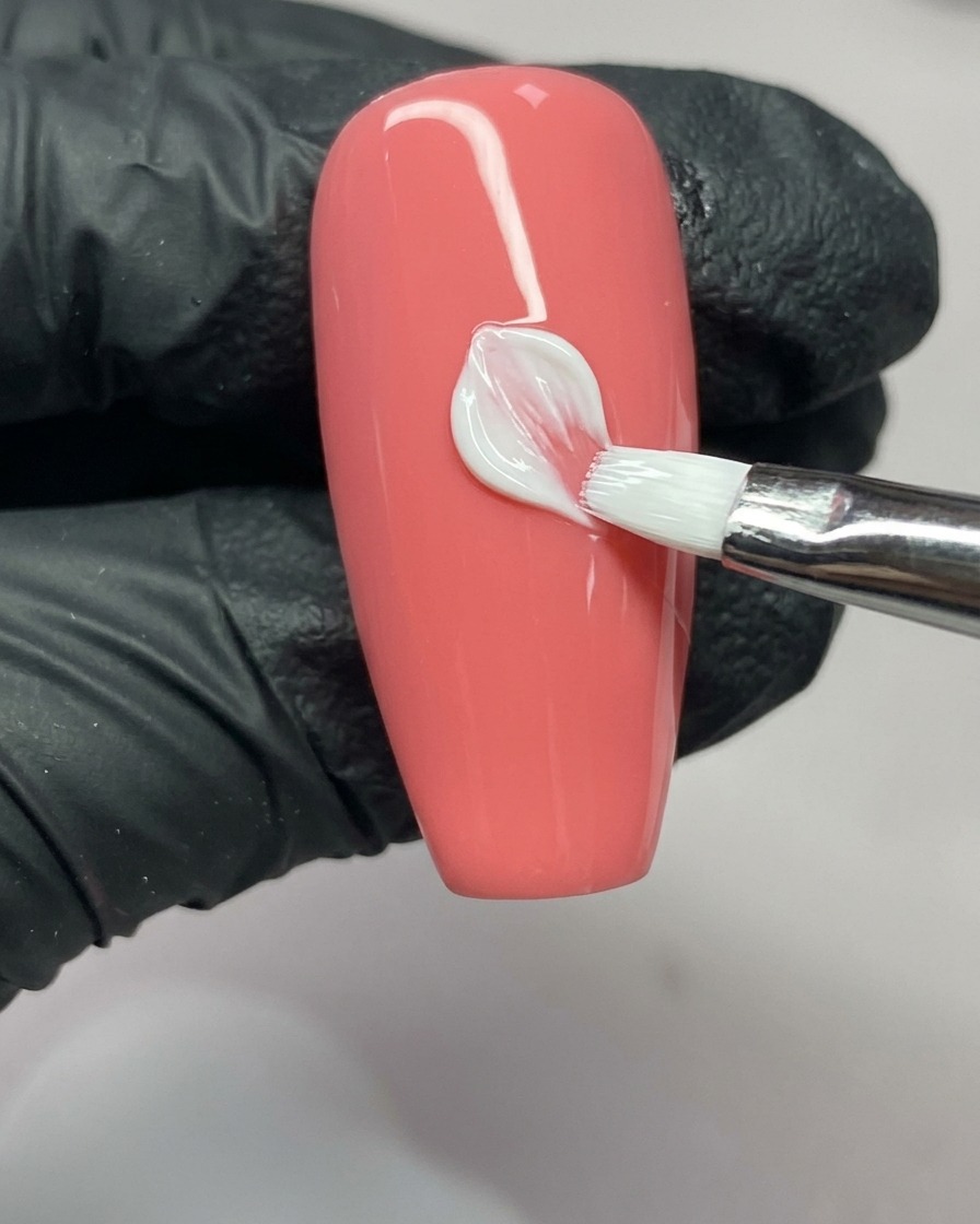 Un pennello per nail art completa il lato destro di un petalo, mostrando la forma a V sulla punta.