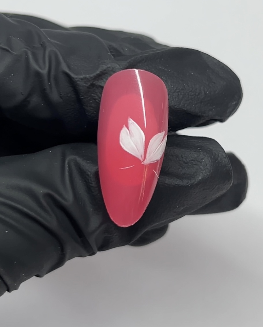 Primo piano di ununghia che mostra tre petali bianchi di un fiore di ciliegio su una base rosa.