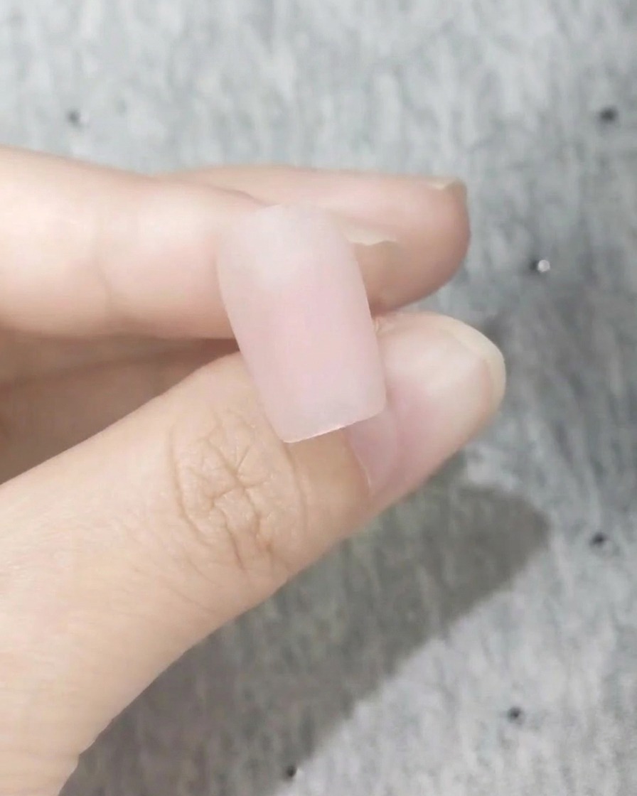 Primo piano di ununghia perfettamente liscia con una finitura rosa blush opaca.
