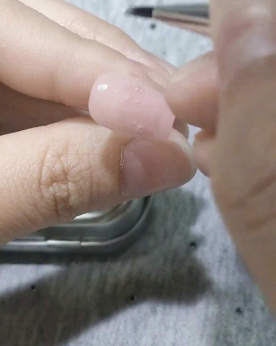 Pennello a punta fine applica gel bianco per formare la forma di un petalo sullunghia.