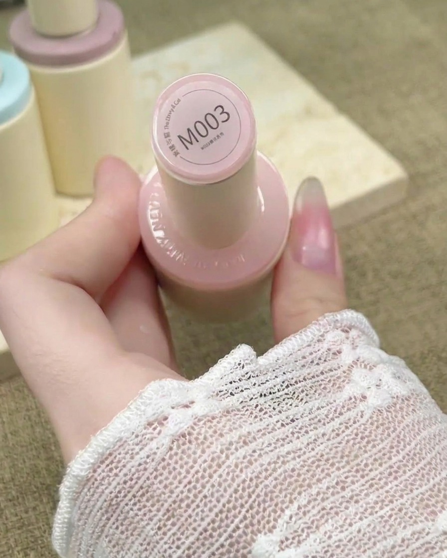 Pennello per unghie che stende uno smalto gel nude rosato trasparente su una ricostruzione.
