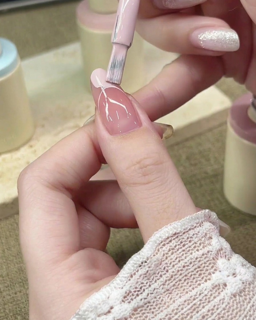 Pennello applicatore che riempie larea del French tip con smalto gel rosa pastello.