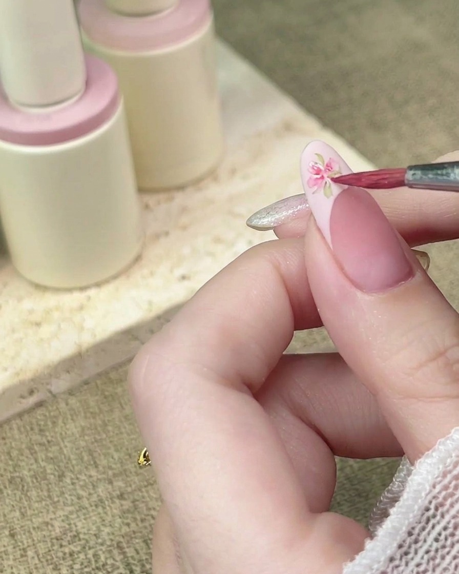 Pennello di precisione che aggiunge altri petali in acquerello rosa per completare il design floreale.
