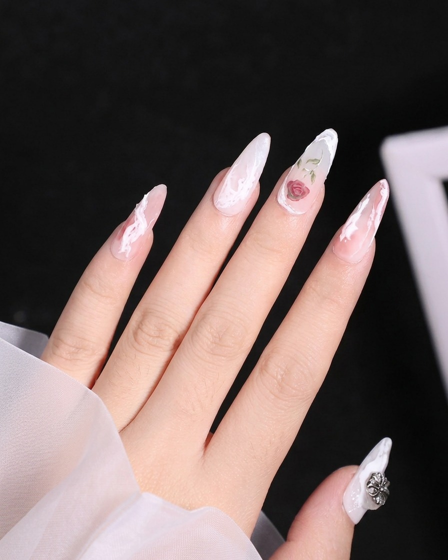Primo piano di un pennello a punta sottile che applica gel bianco per formare i contorni dei petali superiori di una rosa sullunghia.