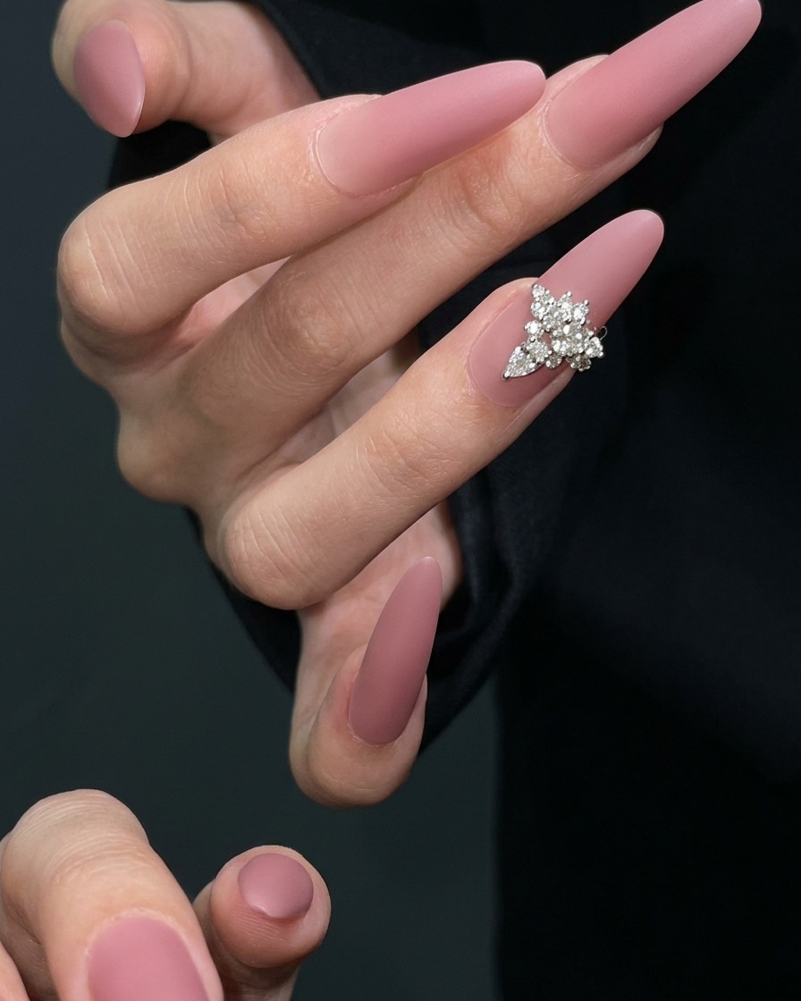 Un pennello per nail art che applica uno strato di top coat gel opaco su ununghia asciutta color malva.