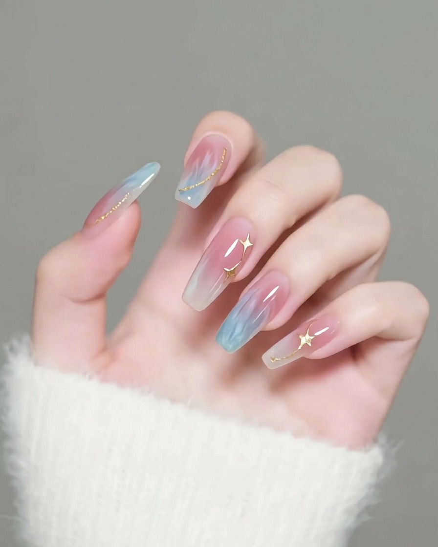 Un pennello applica un top coat trasparente e lucido sopra unghie decorate con stelle dorate.