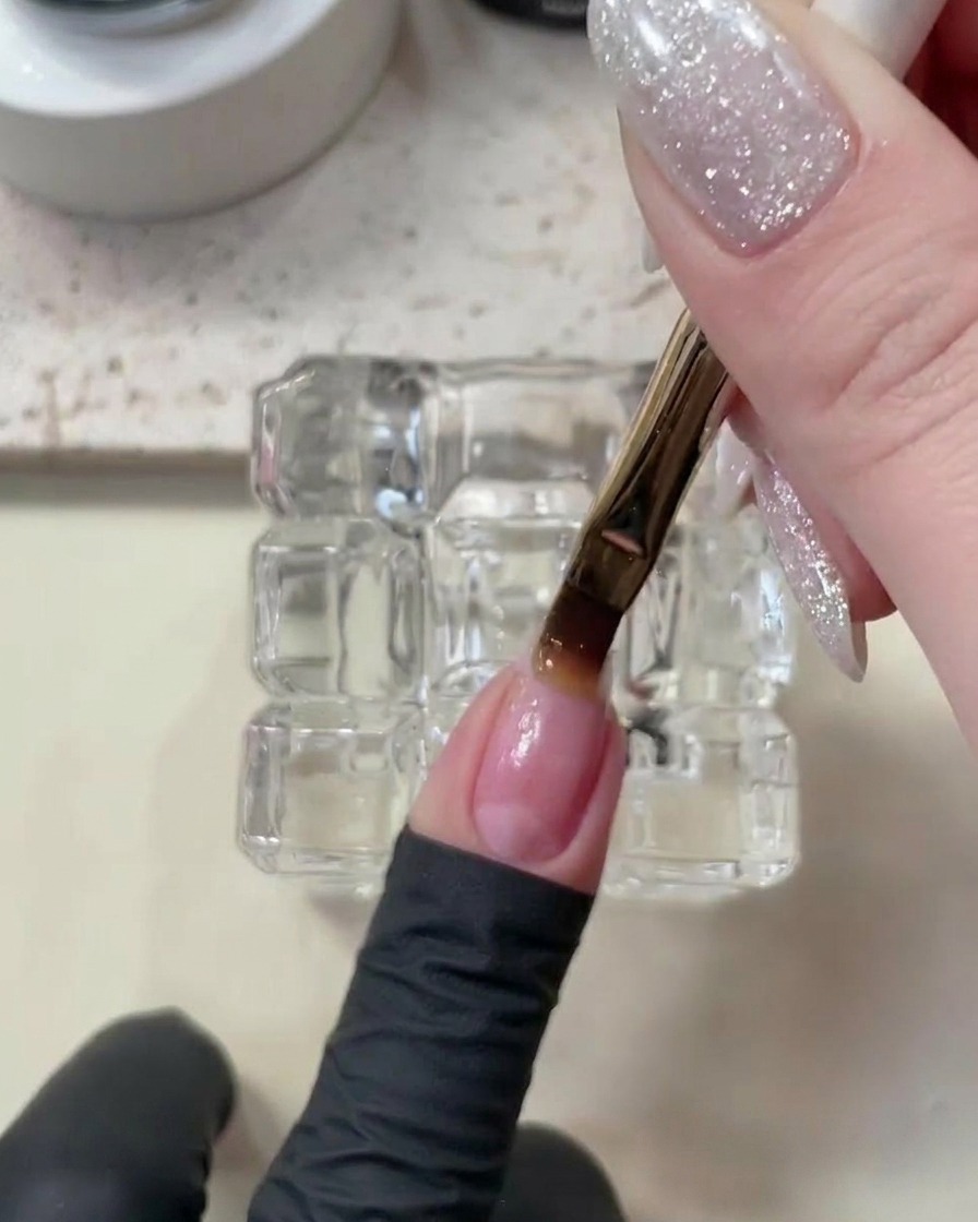 Una mano posizionata allinterno di una lampada UV/LED per unghie, con la base coat in fase di polimerizzazione.