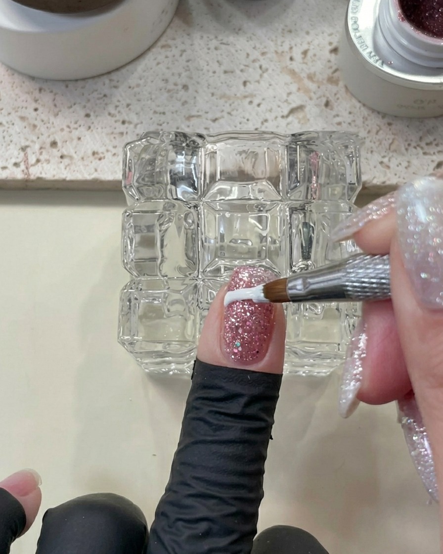 Vista ravvicinata di un dito con gel glitterato pulito con uno strumento, pronto per il processo di polimerizzazione.