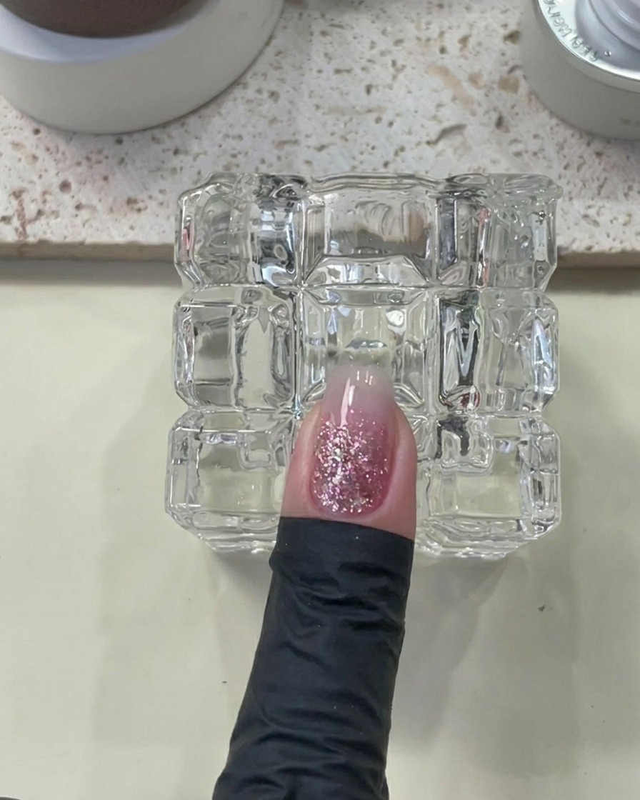 Un dito con gel costruttore applicato, posizionato sotto una lampada UV/LED.