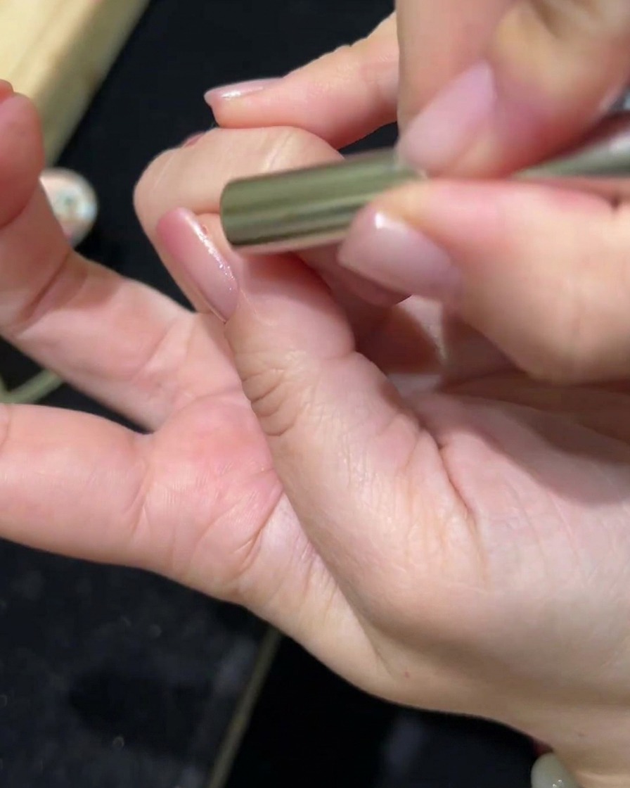 Una bacchetta magnetica tenuta sopra ununghia con gel cat-eye, che mostra il pigmento spostarsi per creare un effetto magnetico.