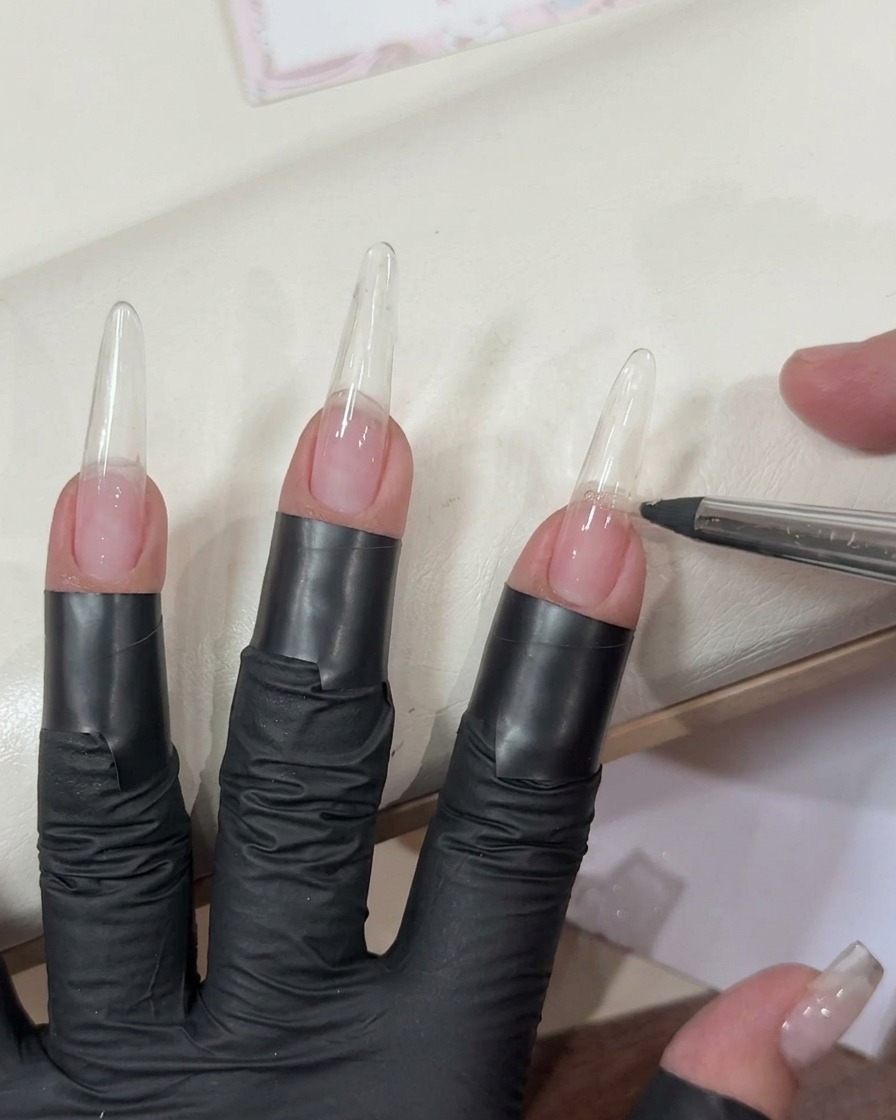 Applicazione di un gel rosa chiaro trasparente su una tip lunga trasparente usando un pennello piatto.