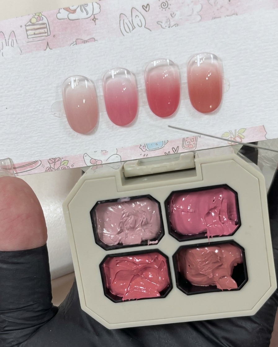 Una piccola quantità di gel rosa cremoso depositata su una superficie bianca accanto alla palette principale.