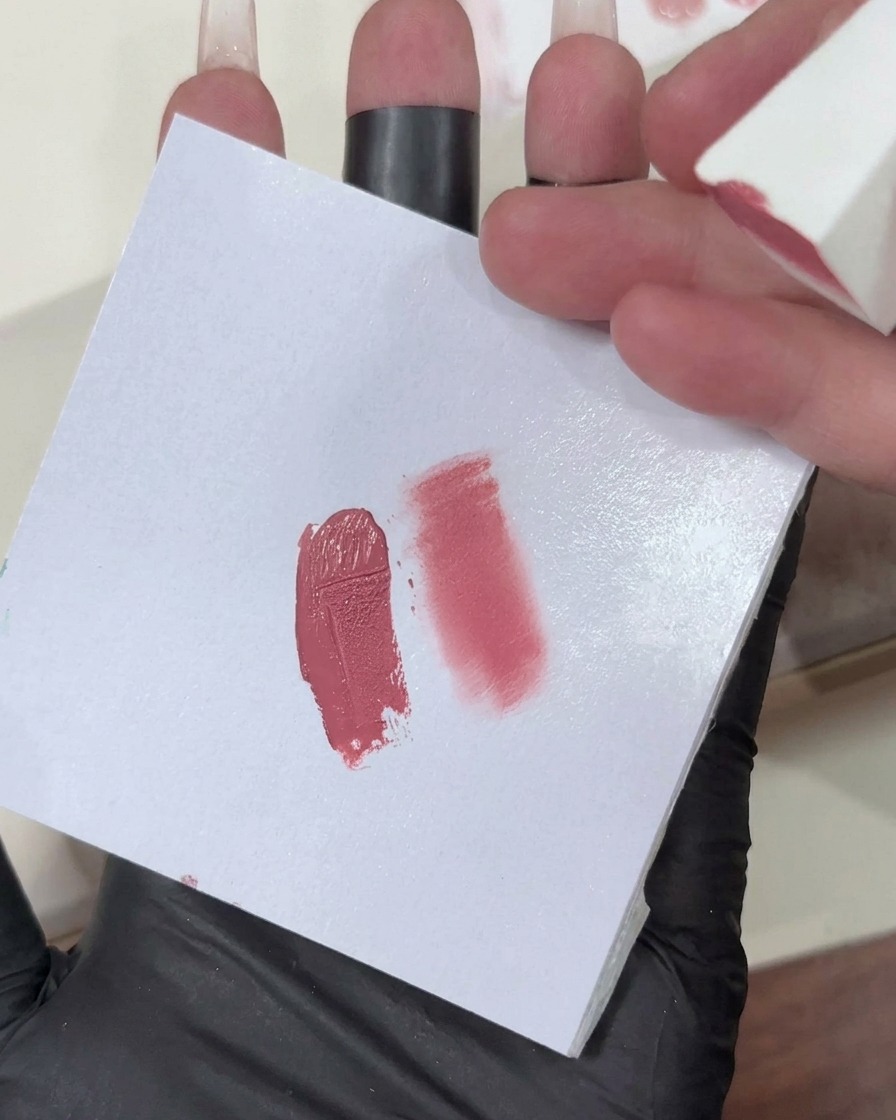 Una spugnetta per il trucco con un gradiente di gel rosa chiaro applicata sulla punta di ununghia.