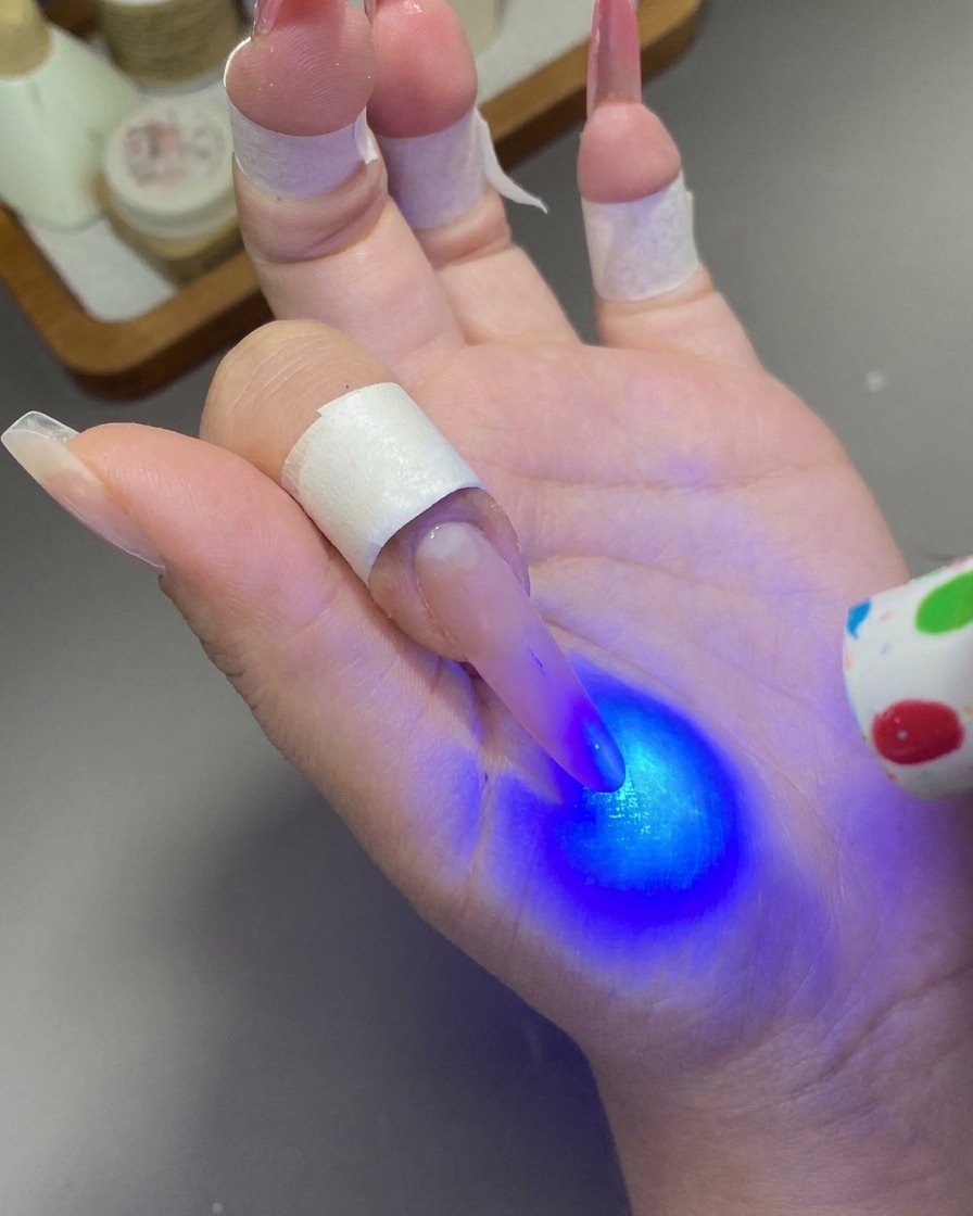 Una mini lampada UV/LED portatile che emette luce blu sullunghia per polimerizzare il gel.