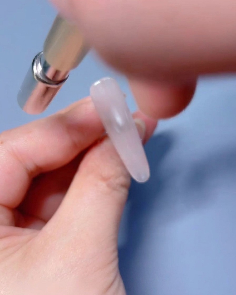 Uno strumento magnetico tenuto vicino allunghia con gel umido per manipolare le particelle brillanti.