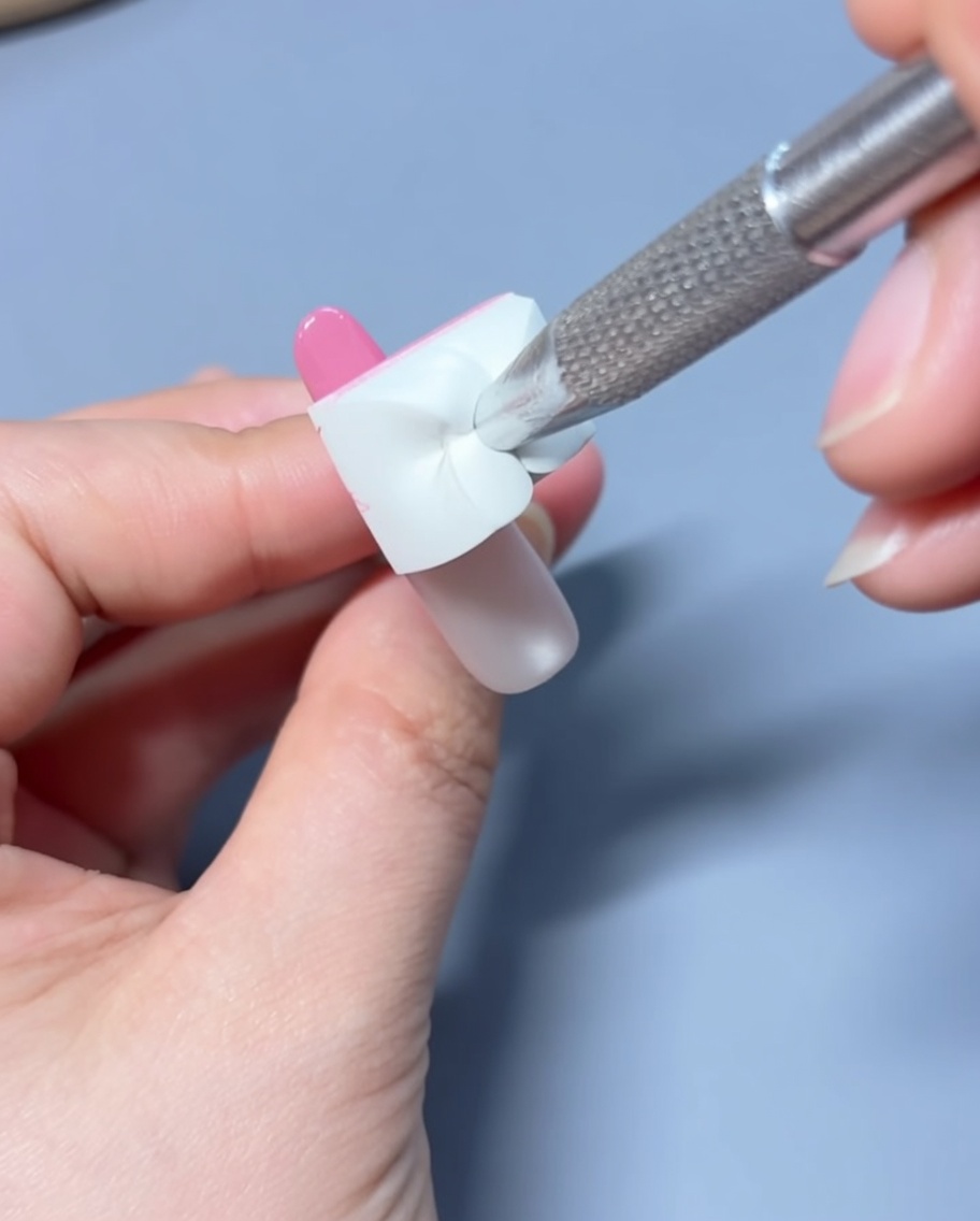 Applicazione di una goccia di smalto gel rosa sulla punta dellunghia preparata.