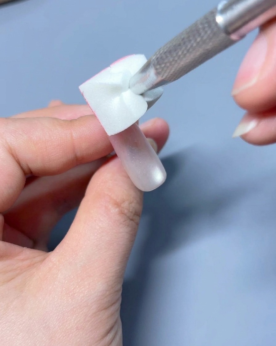 Un pennello piatto per gel mentre sfuma delicatamente il colore rosa sulla superficie dellunghia.
