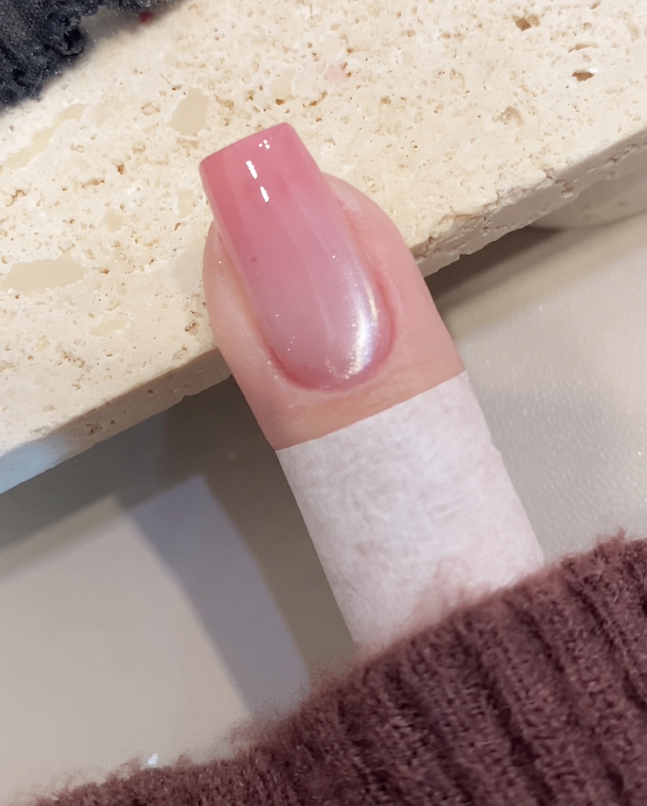 Un primo piano che mostra un pennello mentre applica gel cat-eye scintillante su ununghia preparata.