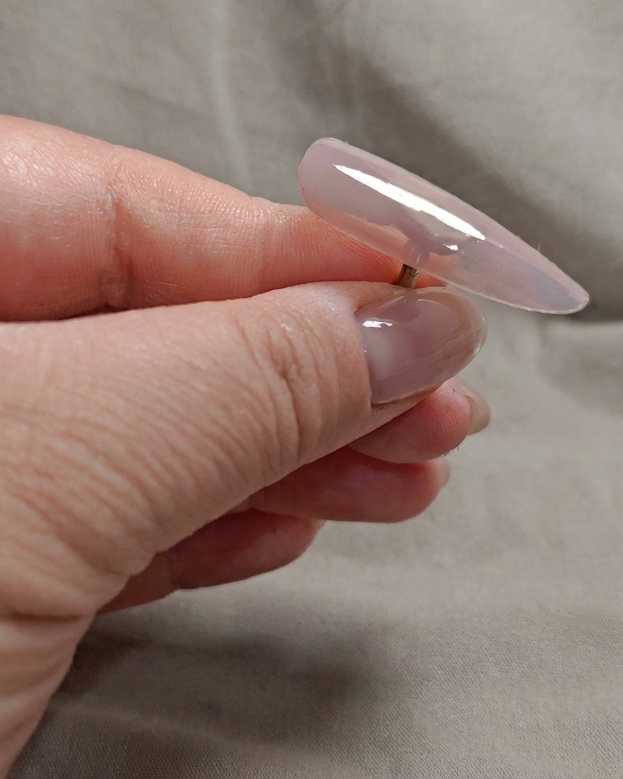 Un pennello applica un secondo strato di gel rosa nude trasparente sulla punta dellunghia.
