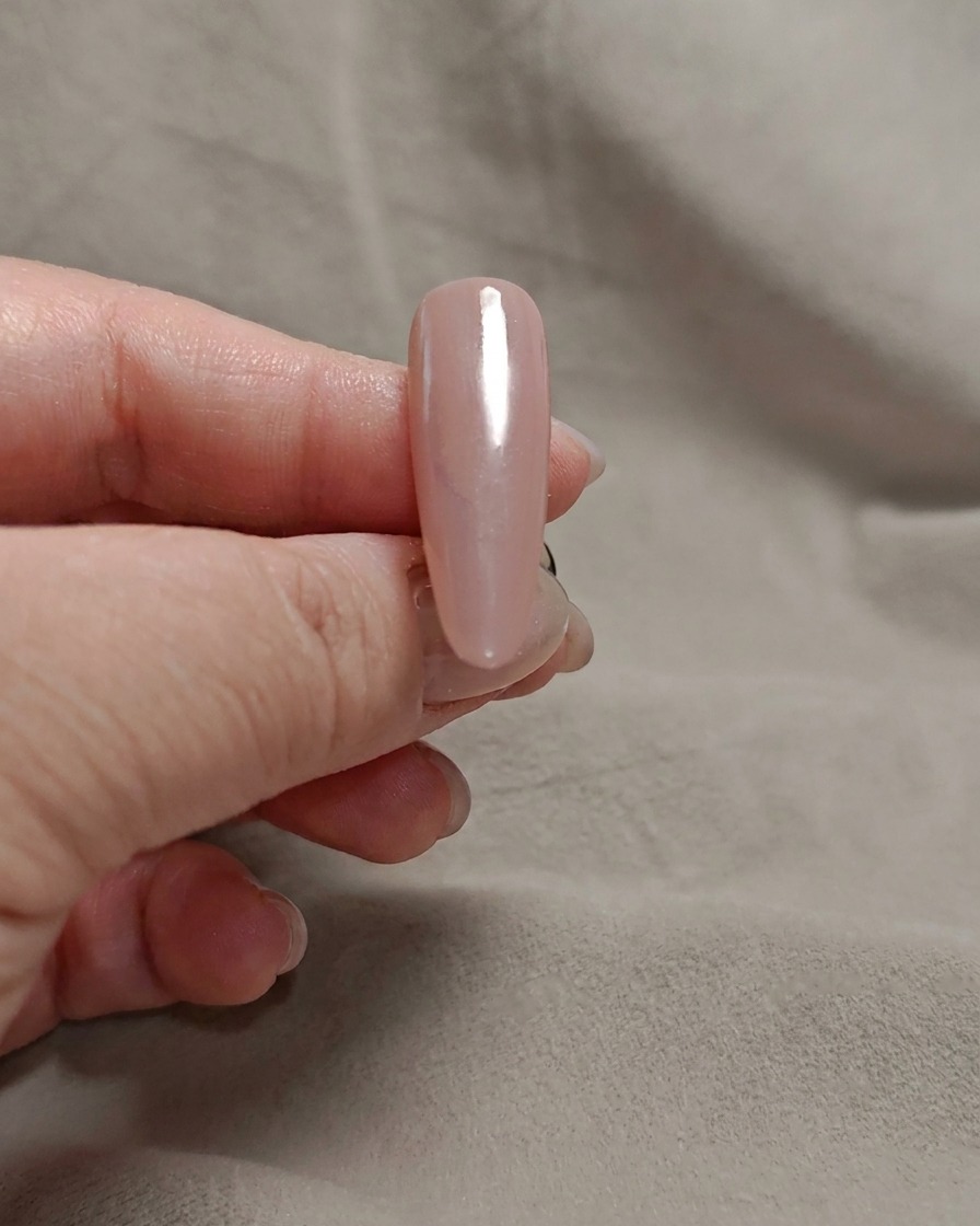Una spugnetta per makeup tampona gel bianco latte sulla punta di ununghia rosa.