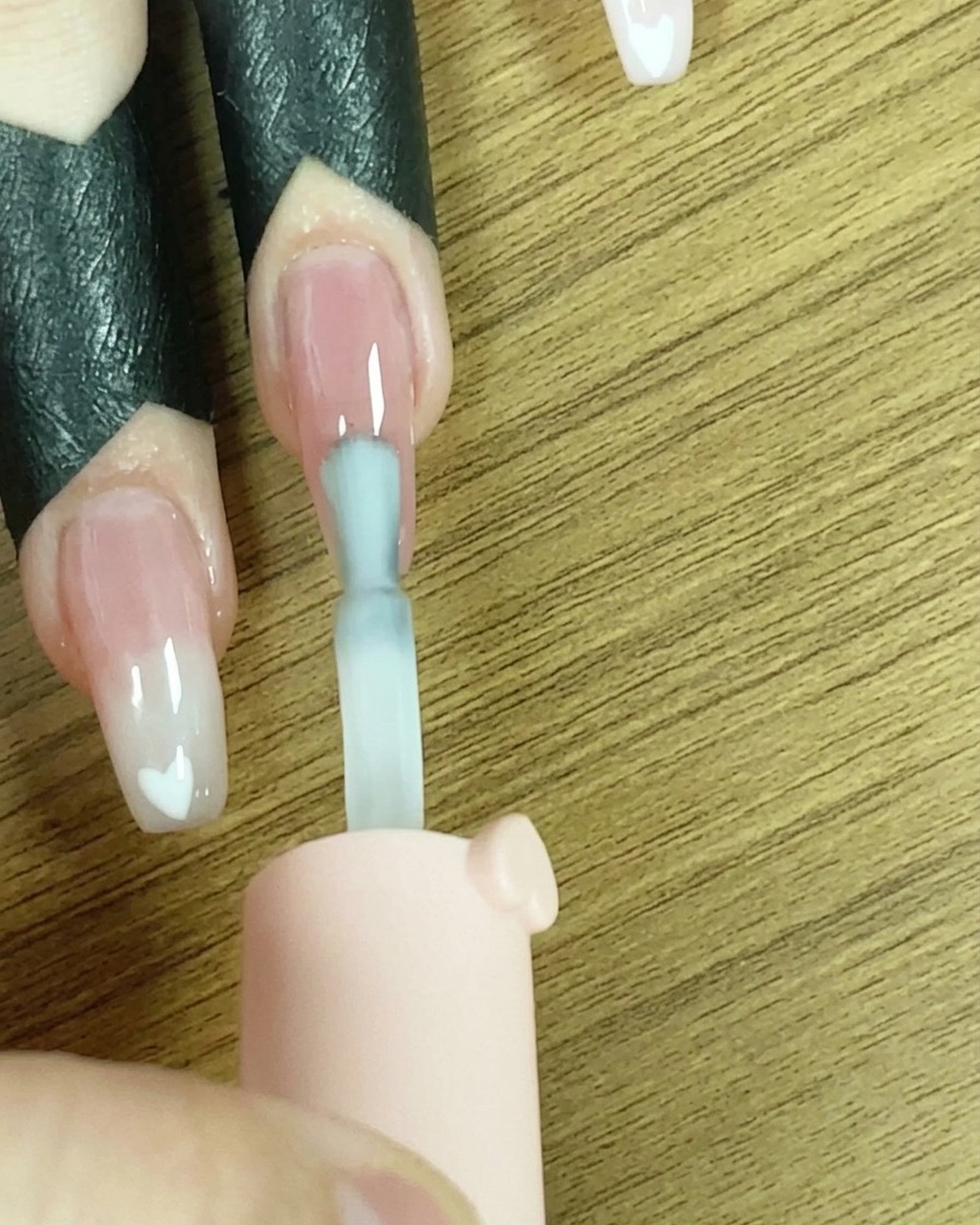 Un pennello che applica una linea di smalto gel bianco sulla punta dellunghia.