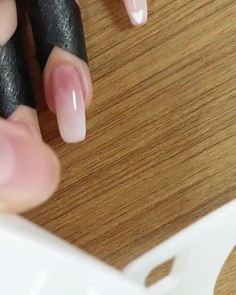 Una mano allinterno di una lampada UV/LED che polimerizza il design delle unghie sfumate.
