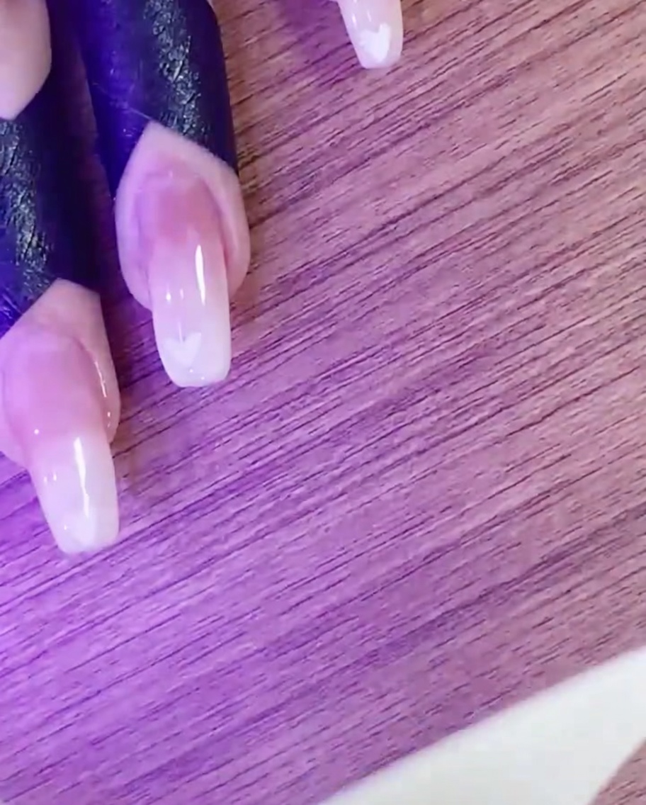 Una mano che polimerizza il design della nail art a cuore sotto una lampada UV/LED.