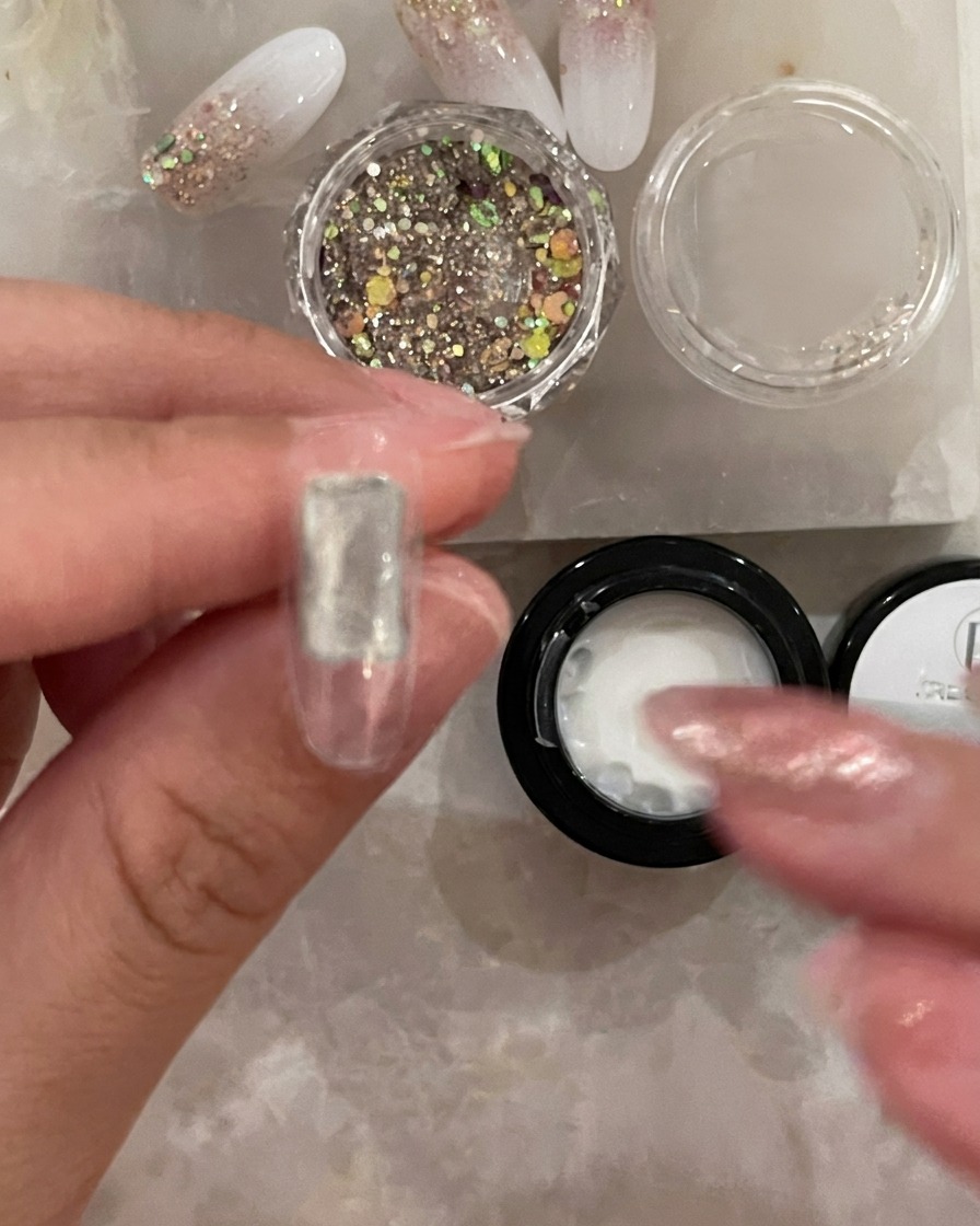 Un pennellino applica uno strato sottile di base trasparente al centro di una tip per unghie artificiale.