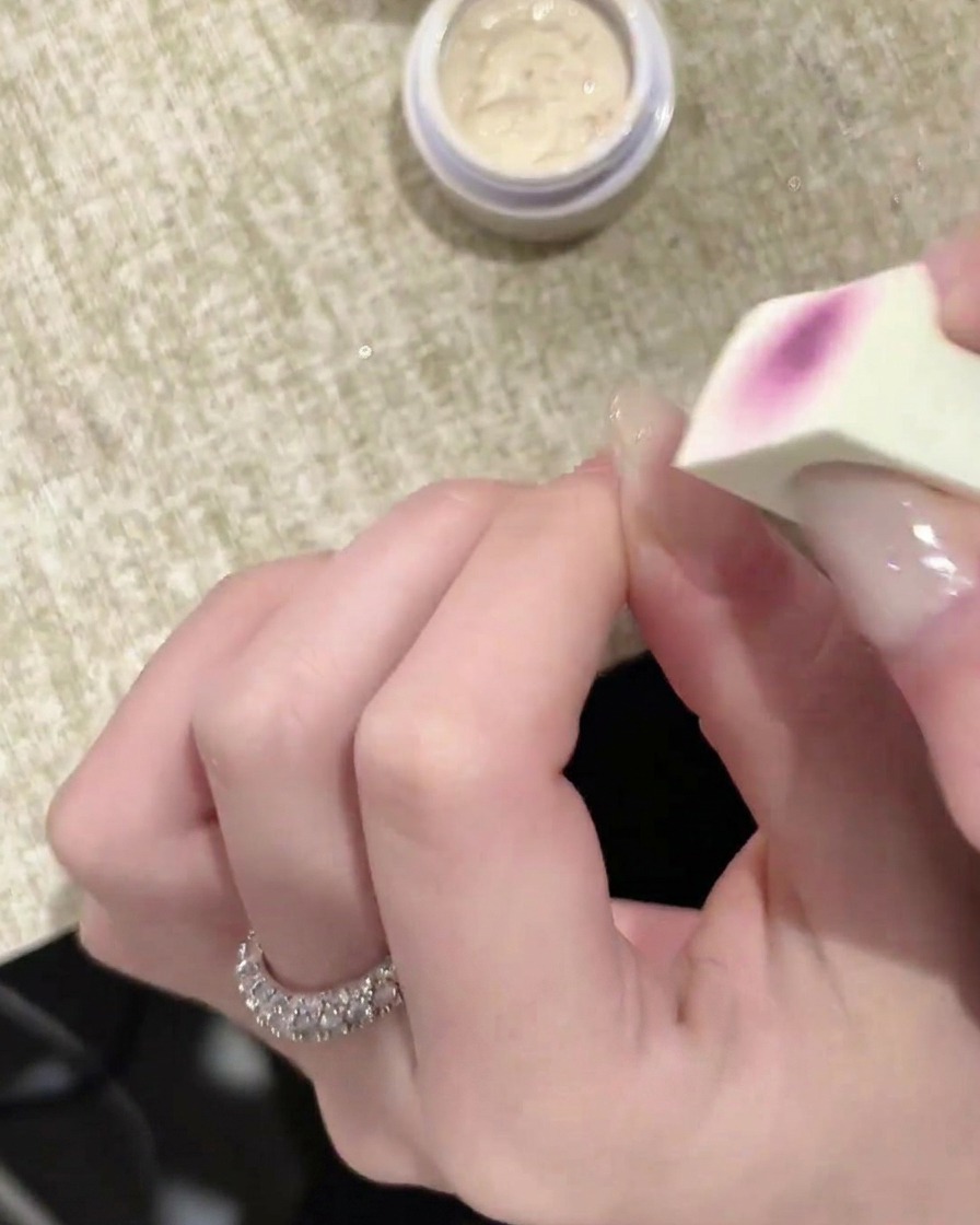 Un applicatore in spugna che stende uno strato di gel bianco su ununghia.