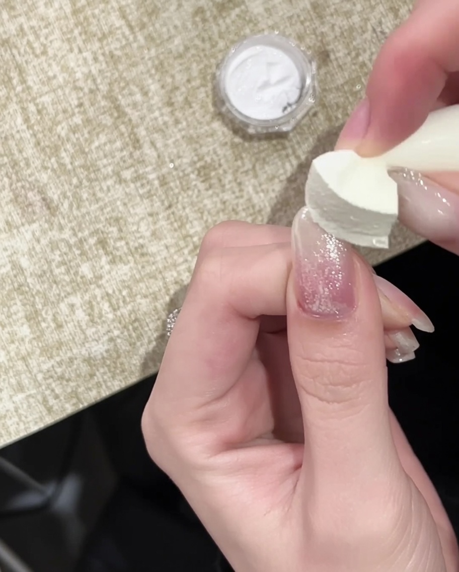 Un pennello che applica un top coat finale lucido sopra lunghia con punta cromata oro.