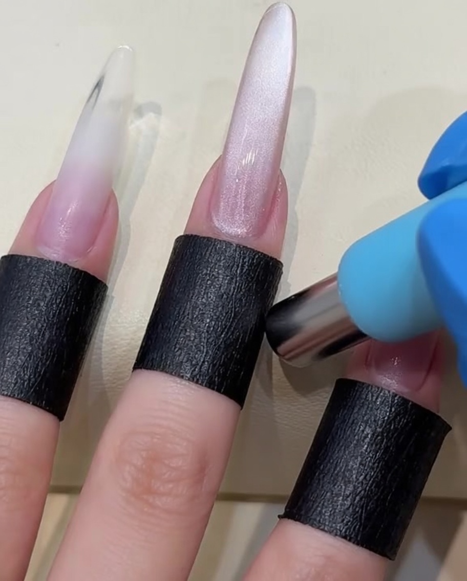 Un magnete cilindrico tenuto vicino a ununghia con gel bagnato per spostare le particelle magnetiche.